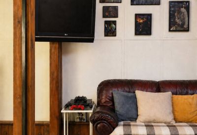 Cozy seating area with a dark leather sofa, colorful pillows, and a wall-mounted TV.