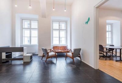 Bright communal lounge area with leather chairs, dark tile flooring, and colorful pendant lights.