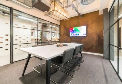 Modern meeting room with a large white table, black chairs, and a geometric feature wall.