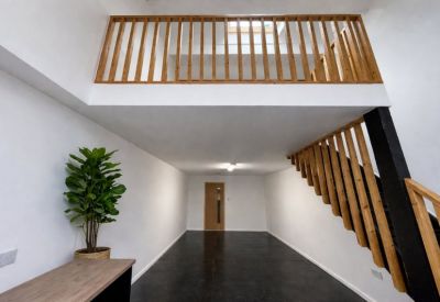 Minimalist white studio space with high ceilings and a mezzanine level.