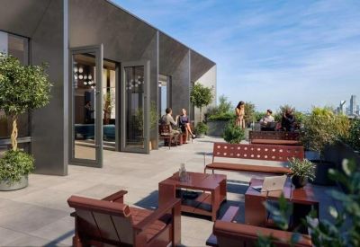 Outdoor roof terrace with wooden seating and lush greenery under a clear blue sky.