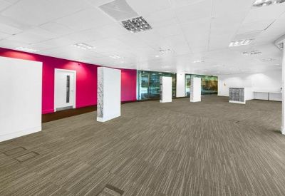 Large empty workspace featuring pink walls and white partition columns under bright LED lighting.