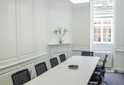 Professional meeting room with white paneled walls and a long conference table.