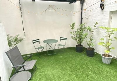 Secluded outdoor patio area with artificial grass and garden furniture.