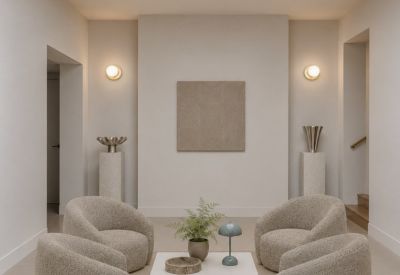Bright communal lounge with plush curved armchairs and a minimalist coffee table under a skylight.