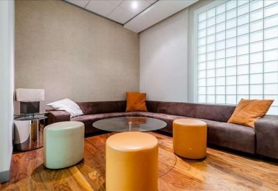 Comfortable breakout lounge with a curved chocolate brown sofa and orange ottomans.