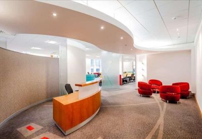 Sleek curved wooden reception desk set against a modern white lobby with red accent chairs.