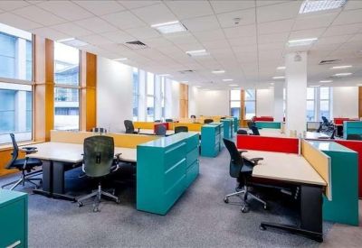 Bright open-plan office with colorful turquoise and red dividers and modern workstations.