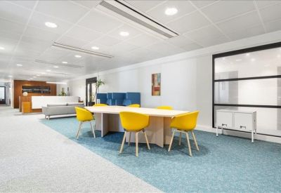 Casual breakout area featuring vibrant yellow chairs and a light wood meeting table.