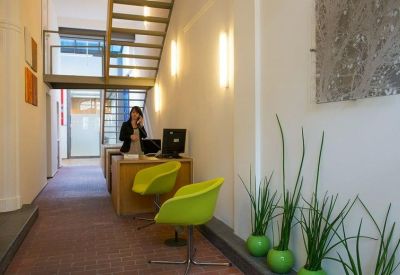 Reception area with a wooden desk, lime green chairs, and a staircase.