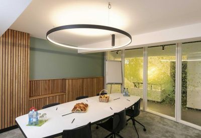 Bright meeting room with a large circular pendant light and wooden wall paneling.