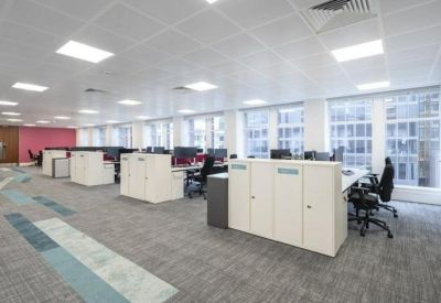 Spacious open-plan workspace with rows of white desks and blue patterned carpeting.