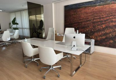 Modern office with sleek white desks and large landscape artwork on wall.