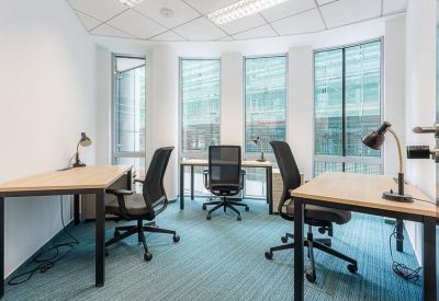 Internal three-person office suite with light wood desks and large windows.