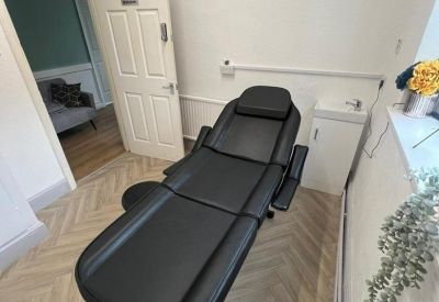 Private treatment suite with a black adjustable therapy chair and herringbone flooring.