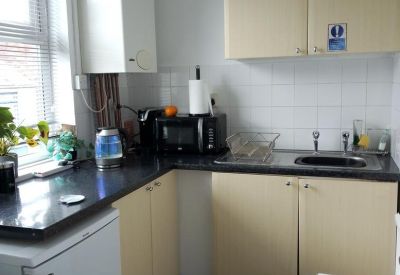 Shared kitchen area with cream cabinetry, dark countertops, and essential appliances.