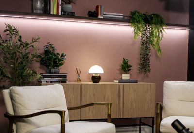 Modern breakout space featuring white armchairs, a wooden sideboard, and a small mushroom lamp.