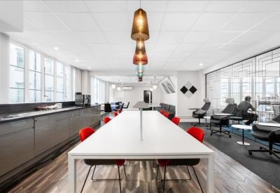Spacious communal breakout area with a long white table and red chairs.
