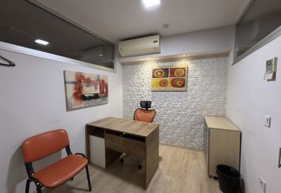 Private office with a wood-toned desk, orange chairs, and a textured accent wall.