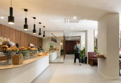 Modern cafe area featuring a long curved white counter and black pendant lighting.