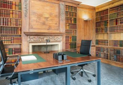 Private office featuring wood paneling, a large fireplace, and built-in bookshelves.