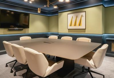 Modern conference room with a large table, tan chairs, and accent lighting.