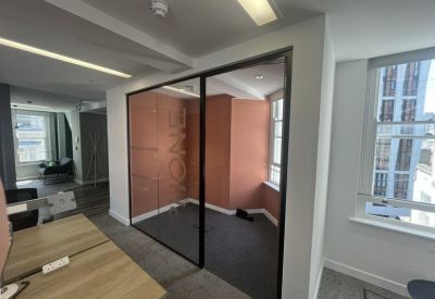 Private office space featuring a pink accent wall behind a glass partition.