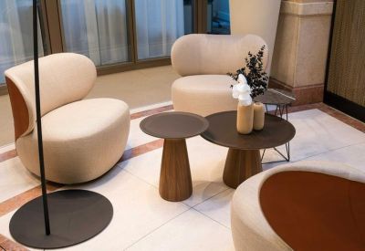 Lounge area with rounded cream armchairs and stylish low circular tables.