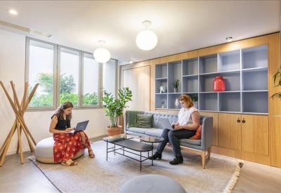 Seating area with a grey sofa, coffee table, and large windows providing natural light.