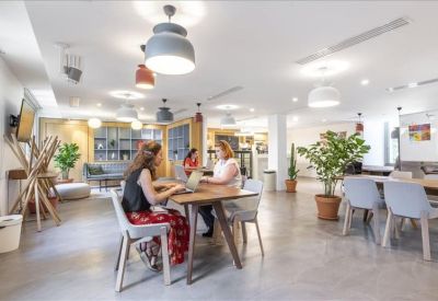 Spacious communal lounge area with mid-century modern furniture and decorative plants.