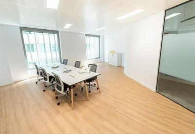 Minimalist conference room with a large white table and frosted glass partitions.
