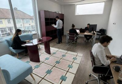 Bright, airy shared workspace with blue sofas, a grid rug, and natural light.