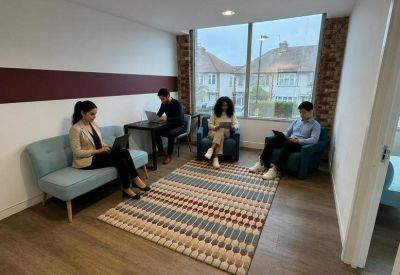 Relaxed breakout area with soft seating, a patterned rug, and a large window.
