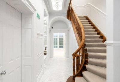 Grand hallway entrance with a sweeping wooden staircase and decorative light panel.