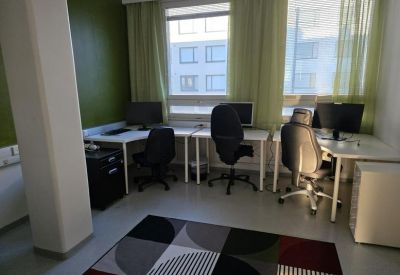 Bright shared workspace with three desks, ergonomic chairs, and large windows.