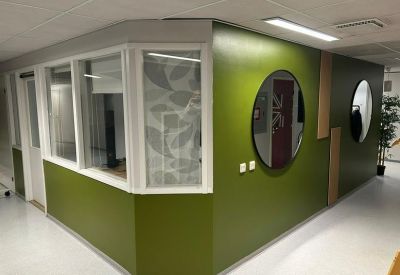 Office hallway featuring a bright green wall and round mirrors.