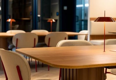 Wooden meeting tables featuring minimalist red designer lamps and cream-colored chairs.