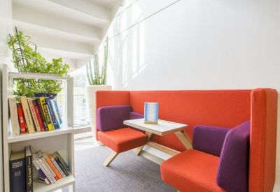 Bright breakout area with orange and purple modular seating and a bookshelf.