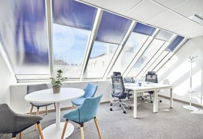 Sunlit open-plan office with slanted glass windows and modern workstations.