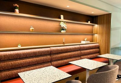 Cozy dining booth with textured backrests and speckled bistro tables against a warm wood wall.
