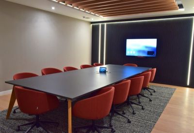 Large boardroom with red ergonomic chairs around a black table under a wood-slatted ceiling.
