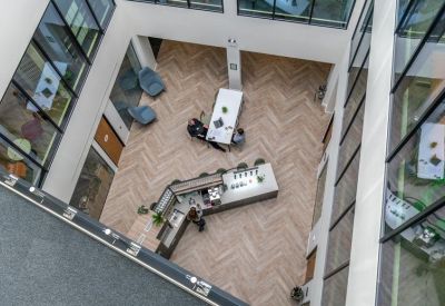 Aerial view of a communal lounge area featuring herringbone flooring and a central coffee bar.