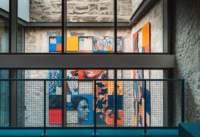 Vibrant wall mural visible through a large glass window and blue industrial railing.