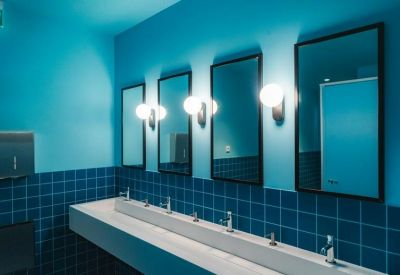 Sleek bathroom with teal walls, round vanity lights, and a continuous trough sink.