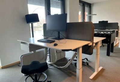 Contemporary workspace with a height-adjustable desk and grey acoustic screen.