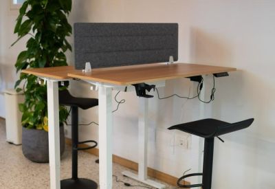 Pair of height-adjustable standing desks with ergonomic stools and privacy screens.