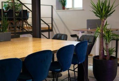 Meeting room at 5a, Via Rauscedo with blue velvet chairs and a large wooden table.