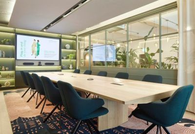 Professional meeting room with a large wooden table, teal chairs, and integrated presentation screen.