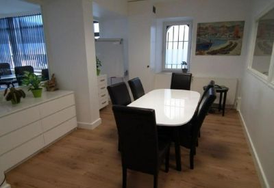Meeting room with a white oval table, black leather chairs, and a bright window.
