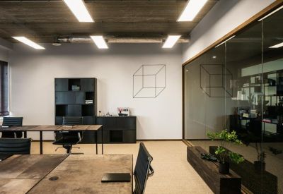 Industrial style office with a concrete ceiling, dark cabinetry, and a glass partition wall.